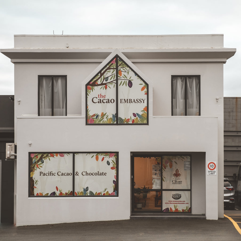 Two-story building with decorative window displays and 'The Cacao Embassy' sign.