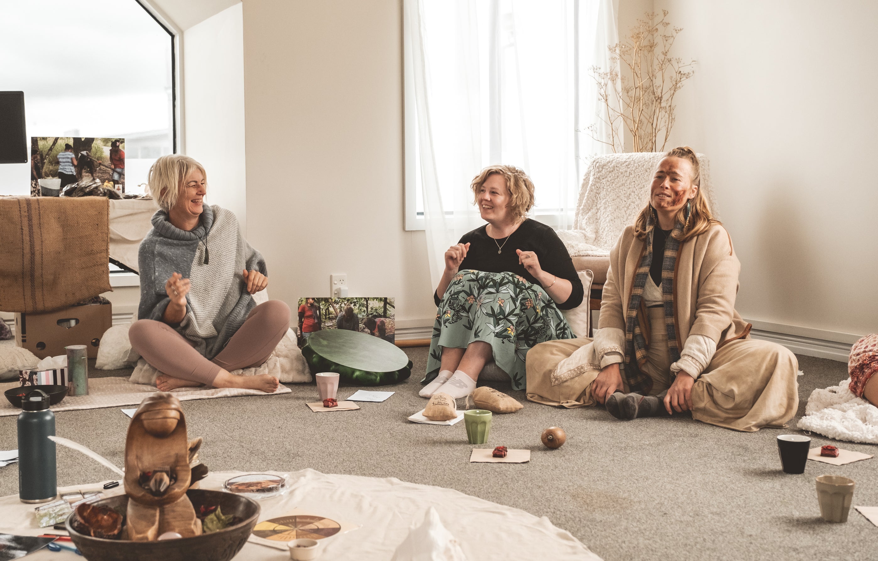 Three women sitting on a floor in a room with a casual and cozy atmosphere.