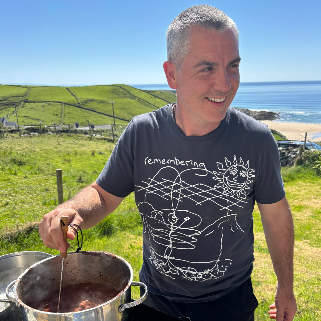 Mar cooking outdoors with a scenic background of green fields and the sea.