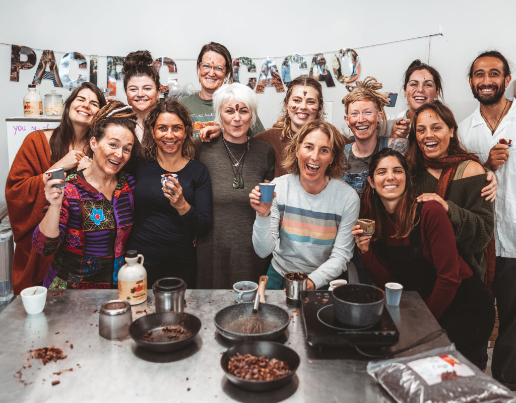 Group of people posing together in a kitchen with cooking ingredients and utensils.