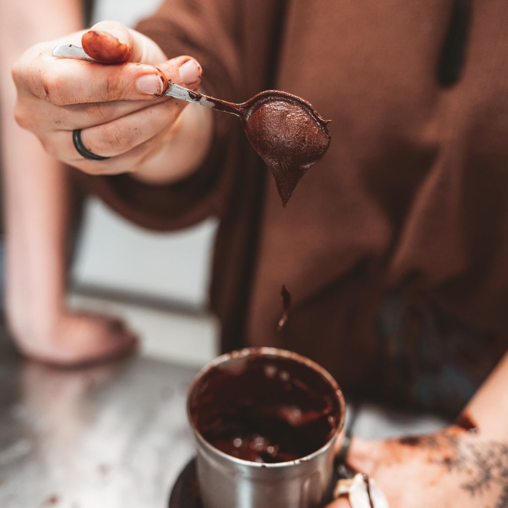 Person holding a spoon with cacao over a mug on a marble surface